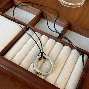 Gros plan d'un collier pendentif circulaire argenté dans un coffret en bois.