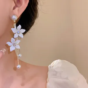 Exquisite Detailaufnahme von Ohrringen mit weißen Blumen und Perlenquasten am Model
