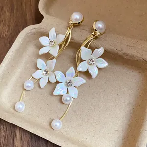 Detailansicht weißer Blumen-Ohrringe mit schillernden Blütenblättern und Perlen