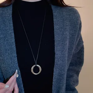 Collier pendentif anneau circulaire minimaliste avec cordon noir sur pull gris détail
