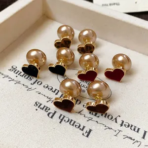 Elegant heart-shaped flocked earrings with champagne pearls on a textured white tray