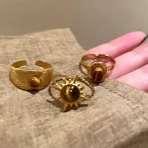 Primo piano di anelli di girasole vintage con finitura dorata e pietre occhio di tigre