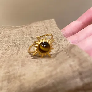 Dettaglio di un anello vintage a sole con pietra occhio di tigre su lino naturale.