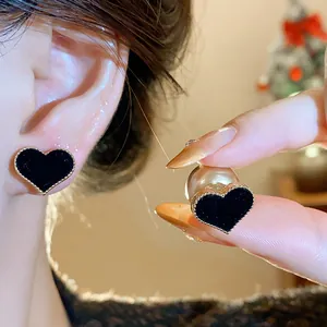 Detailed view of elegant black flocked heart earrings with pearl backings worn on ear