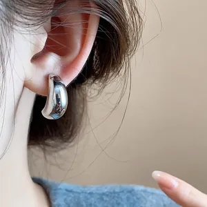 Gros plan d'une boucle d'oreille à clip minimaliste en forme de goutte d'eau argentée