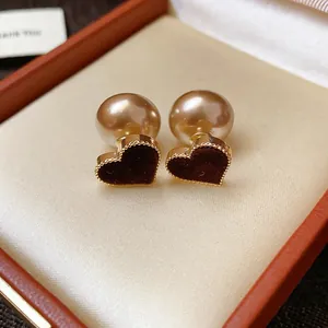 Close-up of elegant flocked burgundy heart earrings with pearl backings in a gift box.