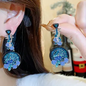 Detailed macro view of blue rhinestone pipa-shaped earrings with delicate rose accents