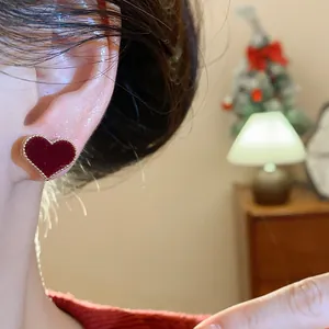 Close-up of red flocked heart stud earring with gold beaded border on ear.