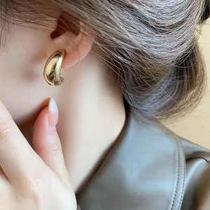 Gros plan d'un clip d'oreille ovale doré minimaliste pour oreilles non percées
