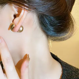 Elegant close-up view showing a gold heart stud earring with a large pearl back on model