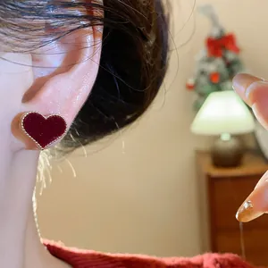 Close-up of red flocked heart stud earrings worn in a warm festive setting