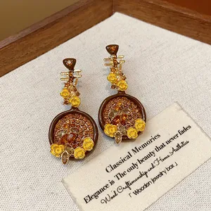 Detailed view of vintage Pipa-shaped earrings with yellow flowers and shiny crystals