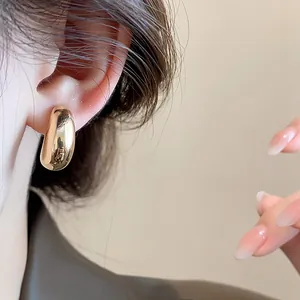 Gros plan détaillé d'un clip d'oreille minimaliste en forme de goutte doré porté à l'oreille