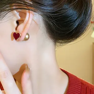 Close-up of red flocked heart stud earrings with golden ball backing on model