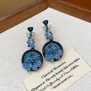 Close-up of vintage Pipa-shaped earrings with blue flower accents and rhinestones.