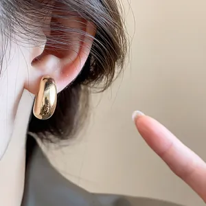 Gros plan d'une élégante boucle d'oreille à clip goutte d'or au fini métallique lisse