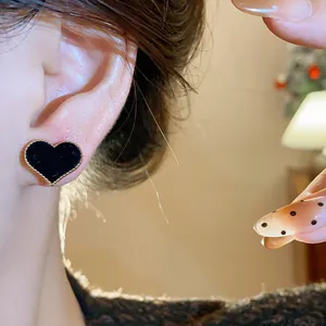 Detailed close-up of a black flocked heart-shaped stud earring with a gold-tone edge.