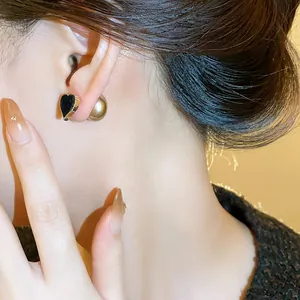 Close-up detail of elegant black flocked heart earrings featuring a gold pearl backing