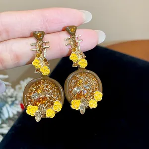 Detailed macro shot of vintage-style lute-shaped earrings with yellow flowers and rhinestones