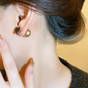 Close-up detail of a flocked heart stud earring with a pearl backing on an ear.