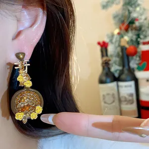 Close-up of vintage pipa-shaped earrings with inlaid crystals and yellow flowers.