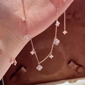 Detail view of rose gold flower charm bracelet with cubic zirconia and shell inlay