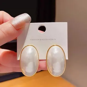 Close-up of elegant oval pearl earrings with gold plating shown on a jewelry card
