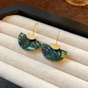 Close-up of vintage fan-shaped earrings with green marbled pattern in a display box