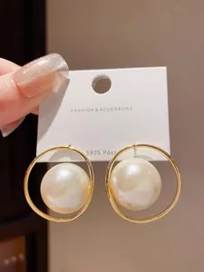 Close-up of elegant gold-plated hoop earrings with large lustrous white pearls.