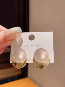 Macro detail of elegant gold-plated stud earrings with translucent round pearls