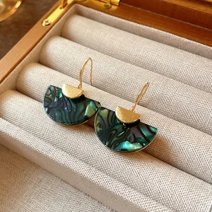 Macro view of vintage marbled fan-shaped drop earrings in a wooden jewelry box