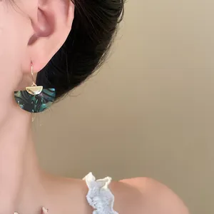Close-up shot of elegant vintage marbled fan-shaped drop earrings worn by a model