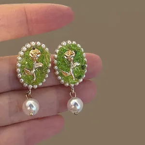 Macro close-up of vintage style green rose earrings with elegant pearl drop detail