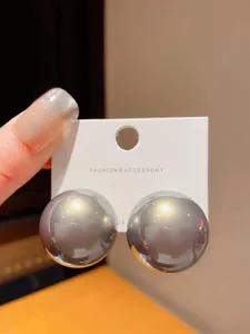 Close-up of large grey spherical stud earrings held on a display card with S925 silver needle