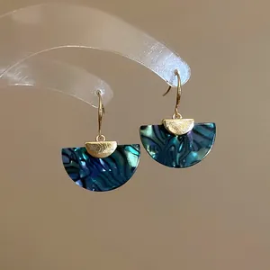 Detail of fan-shaped drop earrings with teal ink-wash pattern and gold hooks