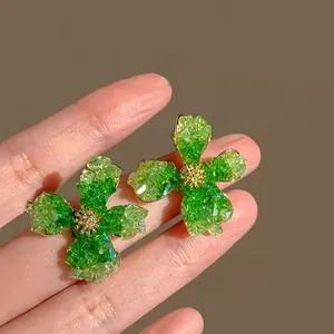 Detailed macro view of green floral earrings with crushed crystal texture and gold centers