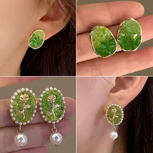 Detailed view of green forest-style floral earrings with elegant rose and pearl drops.