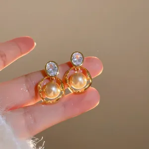 Detailed close-up of vintage gold-plated earrings featuring oval zircon and elegant cream pearls