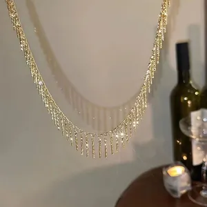 Détail rapproché d'un collier à franges doré minimaliste sous une lumière chaude
