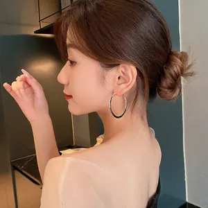 Elegant detail of a large minimalist gold hoop earring worn by a model in profile view