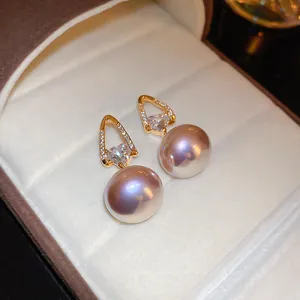 Macro detail view of elegant gold-plated heart CZ earrings with large lavender pearls