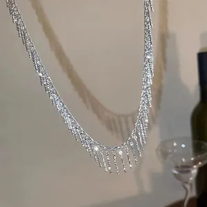 Un gros plan d'un collier à pompons argentés minimaliste avec des détails scintillants.
