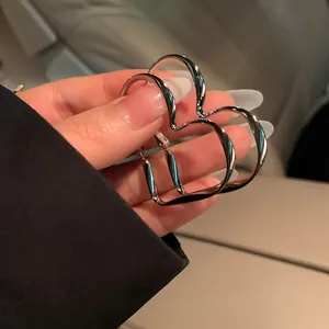 Detailed view of luxury silver-toned heart hoop earrings held for style showcase