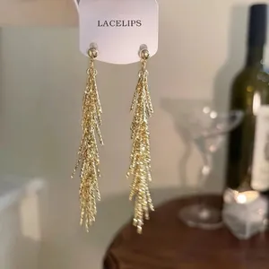 Vue détaillée de boucles d'oreilles pendantes à glands dorés sur une carte de présentation