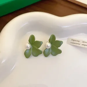 Close-up detail of forest-style green flower stud earrings with elegant pearl centers