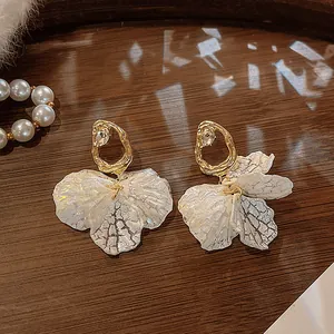Macro view of vintage French-style earrings with shell petals and gold studs