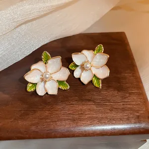 Close-up detail of vintage floral stud earrings with pearly petals and green leaves