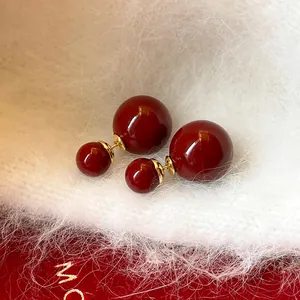 Vista dettagliata degli orecchini a doppia sfera rossa su elegante tessuto bianco