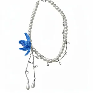 Elegant pearl necklace featuring a blue beaded flower and teardrop charms on silver chain