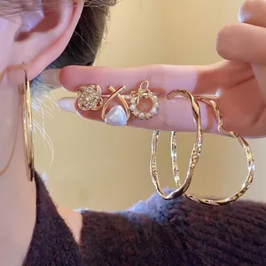 Elegantes Set aus unregelmäßigen goldenen Ohrringen mit Perlen und Strasssteinen